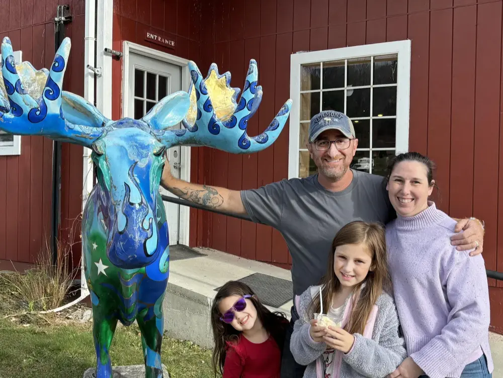 Tim Walt with his wife and two daughters beside a painted moose statue in Vermont